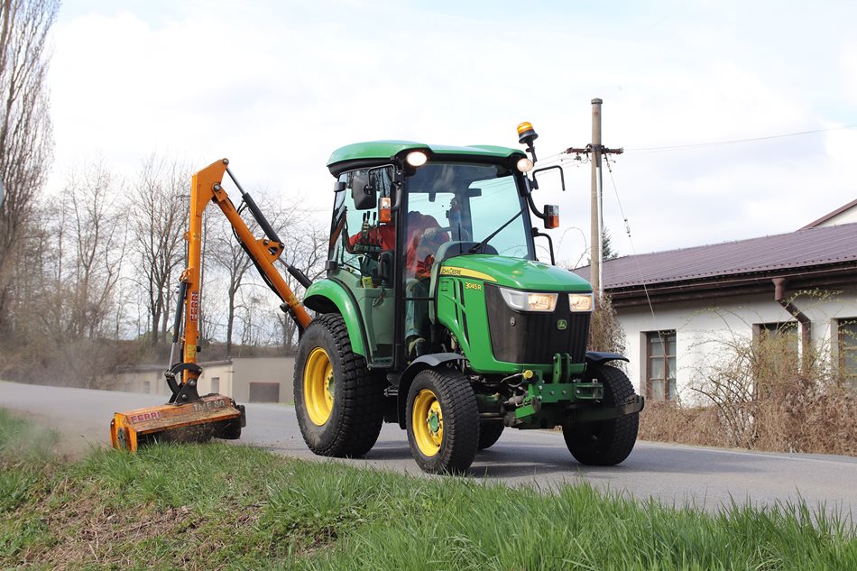 Traktor John Deere 3045R udržuje plochy kolem silnic příkopovým mulčovačem Ferri