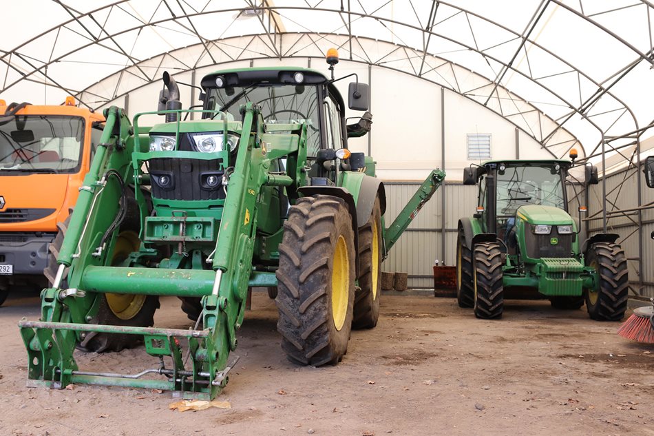 Velký traktor John Deere 6115M (vlevo) zpracovává svezený bioodpad drtičem Ecogreen. Traktor John Deere 5085M (vpravo) pracuje v soupravě s příkopovým ramenem Kuhn nebo v zimě se vzadu nesenou radlicí